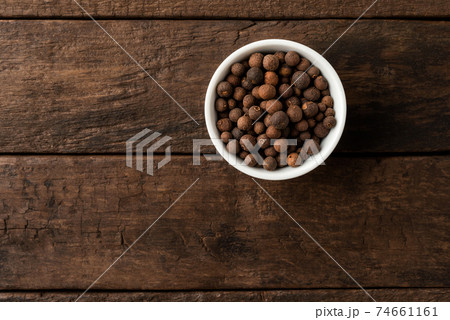 Allspice in bowl on retro wooden background. Top view Allspice in bowl on retro wooden background. Top view 74661161