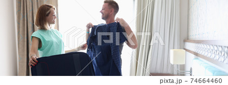 Man try on female jacket with polka dots in room. Man try on female jacket with polka dots in room. 74664460