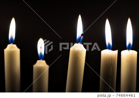 Candles glowing against dark background Candles glowing against dark background 74664461
