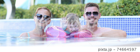 Happy family spend time holiday in pool. 74664597