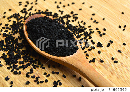 Dry black cumin in wooden spoon, on bamboo cutting board Dry black cumin in wooden spoon, on bamboo cutting board 74665546