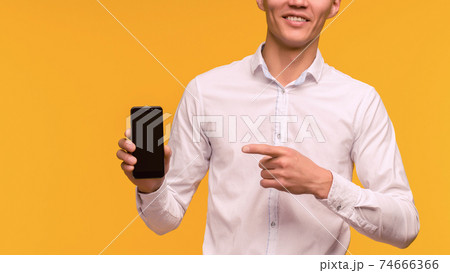 Excited winner Asian man pointing at mobile phone Excited winner Asian man pointing at mobile phone 74666366
