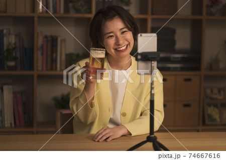 スマホに向かって乾杯する若い女性 スマホに向かって乾杯する若い女性 74667616