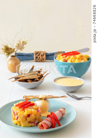Henri Egg, tasty fresh brunch or snack. Henri Egg, tasty brunch or snack. Boiled eggs and smoked sprats fish with mayonnaise, ham and potato salad. White wooden table, no people. 74668826