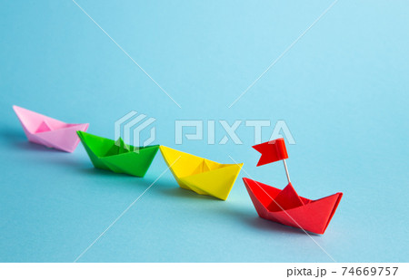 Red leader paper ship leading among others on blue background. Leadership concept. Red leader paper ship leading among others on blue background. Leadership concept. 74669757