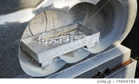 墓石の香炉に設置された線香の燃えカス 74669780