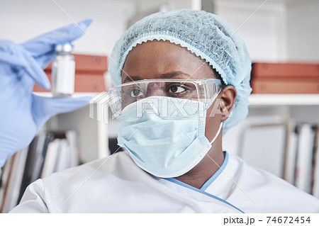 Nurse looking at ampoule while checking the liquid 74672454