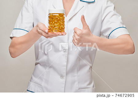 Health care and diet concept - doctor nutritionist or cardiologist holding fish oil in capsules for vitamin D and omega-3 fatty acids 74672905