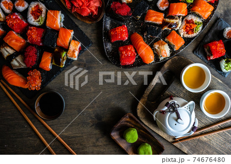 Sushi Set  with various sashimi, sushi rolls and tea  served on stone slate 74676480