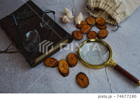 on the table are runes, a book ,a magnifying glass on the table are runes, a book ,a magnifying glass 74677280