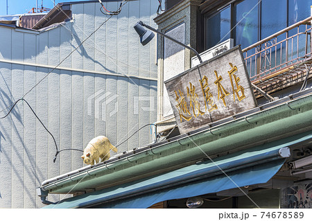 東京 谷中 谷中銀座の有名な商店街の酒屋の越後谷の屋根に立ってる白い猫の彫刻 の写真素材