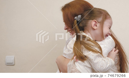Little child hugs mom and laughs. Happy girl rejoices at mommy. A daughter and a woman are playing in the children's room. Mothers Day. Parents' love for kid. Upbringing on maternity leave. Family 74679266