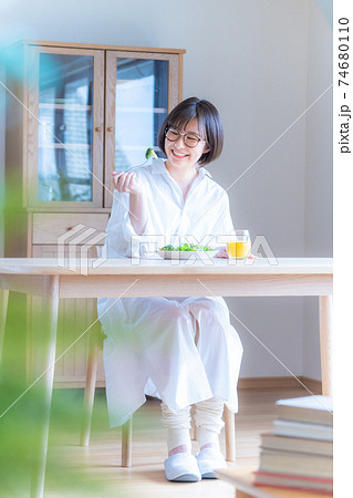朝の日差しの中で食事をする若い女性 朝の日差しの中で食事をする若い女性 74680110