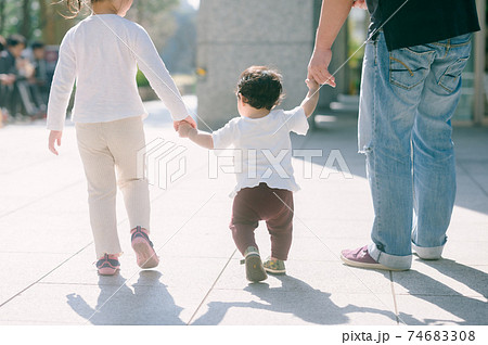 手をつないで家族と歩く赤ちゃん 後ろ姿の写真素材