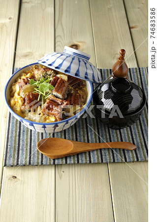 ランチョンマットの上の鰻蒲焼きを卵でとじたうな玉丼とお吸い物のセットと木製スプーン 74683586