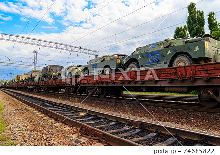 Cargo train carrying military vehicles on railway flat wagons 74685822