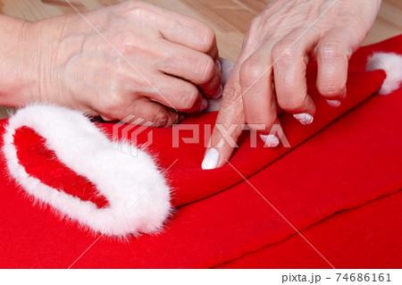 Grandma sewing small Santa hat for grandchildren. 74686161
