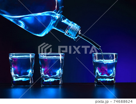 Vodka is poured into a glass . 74688624