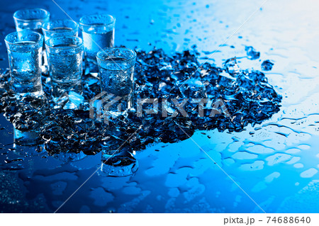 Damp glasses of vodka with ice on a black reflective background. Damp glasses of vodka with ice on a black reflective background. 74688640