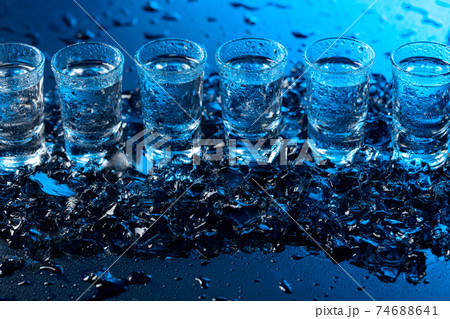 Damp glasses of vodka with ice on a black reflective background. Damp glasses of vodka with ice on a black reflective background. 74688641