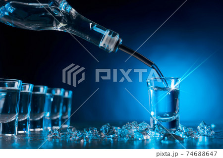 Vodka poured into a glass lit with blue backlight. 74688647