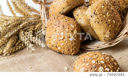 Rustic bread. Fresh loaf of rustic traditional bread with wheat grain ear or spike plant on linen texture background. Rye bakery with crusty loaves and crumbs. Concept - Cooking at Home. 74692085
