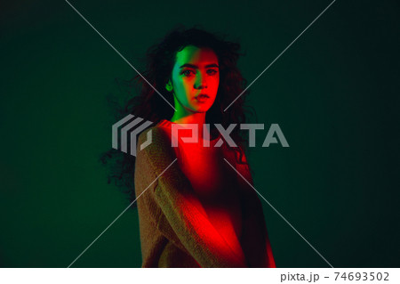 Caucasian woman's portrait isolated on green studio background in multicolored neon light 74693502