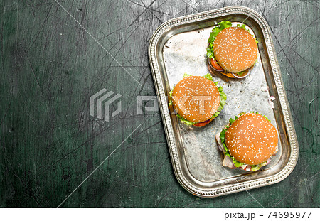 Burgers from fresh beef and vegetables with different sauces on a steel tray. Burgers from fresh beef and vegetables with different sauces on a steel tray. 74695977