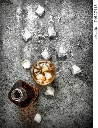 glass of whiskey with ice cubes. glass of whiskey with ice cubes. 74697418