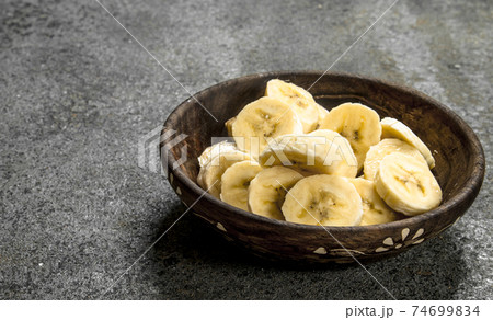 Sliced bananas in a bowl. 74699834