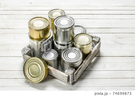 Tin cans with food in a box. Tin cans with food in a box. 74699873