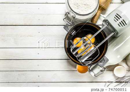 Baking background. Fresh eggs with a mixer. 74700051