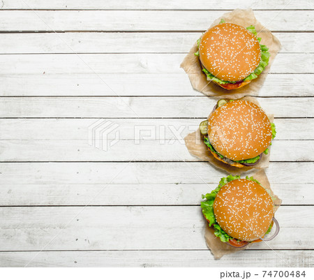 Burgers with beef, cheese and vegetables on paper. 74700484