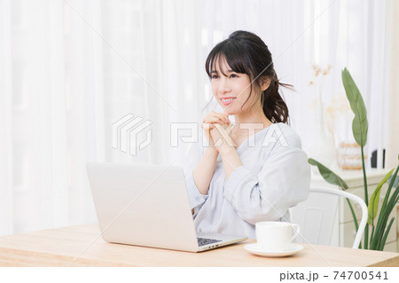 部屋でノートパソコンを使いながらお願いのジェスチャーをする若い女性 部屋でノートパソコンを使いながらお願いのジェスチャーをする若い女性 74700541
