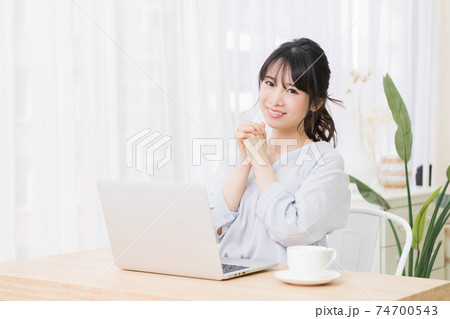 部屋でノートパソコンを使いながらお願いのジェスチャーをする若い女性 部屋でノートパソコンを使いながらお願いのジェスチャーをする若い女性 74700543