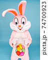 Easter bunny or rabbit or hare holds basket of colored eggs, having fun, dancing, celebrates Happy easter. Easter rabbit isolated on blue background 74700923