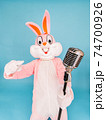Positive funny man or kid singer or vocalist sings song to retro vintage classic microphone. Easter bunny or rabbit or hare celebrates Happy easter isolated on blue 74700926