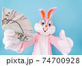 Rich lucky happy man or boy or kid millionaire or billionaire holds fan of dollars, shows thumb finger up, having fun. Easter bunny or rabbit or hare with dollar, celebrate Happy easter 74700928