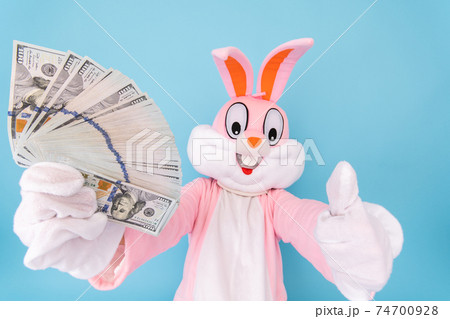 Rich lucky happy man or boy or kid millionaire or billionaire holds fan of dollars, shows thumb finger up, having fun. Easter bunny or rabbit or hare with dollar, celebrate Happy easter Rich lucky happy man or boy or kid millionaire or billionaire holds fan of dollars, shows thumb finger up, having fun. Easter bunny or rabbit or hare with dollar, celebrate Happy easter 74700928