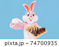 Man or kid chess player plays move chess piece, fooling around, throwing chess. Easter bunny or rabbit or hare having fun celebrates Happy easter 74700935