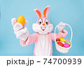 Easter bunny or rabbit or hare holds egg with basket of colored eggs, having fun, celebrates Happy easter. Easter rabbit isolated on blue background 74700939