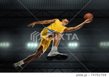 Young professional basketball player in action, motion isolated on black background, look from the bottom. Concept of sport, movement, energy and dynamic. 74701709