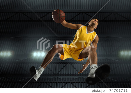 Young professional basketball player in action, motion isolated on black background, look from the bottom. Concept of sport, movement, energy and dynamic. Young professional basketball player in action, motion isolated on black background, look from the bottom. Concept of sport, movement, energy and dynamic. 74701711