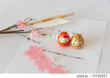 入試の合格証書とダルマ、合格祈願の破魔矢、桜の花びら 入試の合格証書とダルマ、合格祈願の破魔矢、桜の花びら 74702637