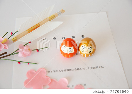入試の合格証書とダルマ、合格祈願の破魔矢、桜の花びら 74702640