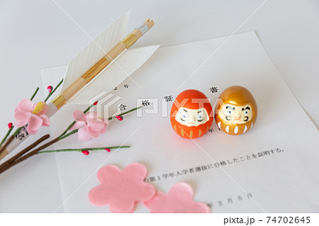 入試の合格証書とダルマ、合格祈願の破魔矢、桜の花びら 74702645