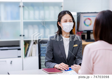 マスクをつけて接客をする女性 74703098