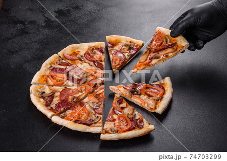 Fresh delicious pizza made in a hearth oven with sausage, pepper and tomatoes 74703299
