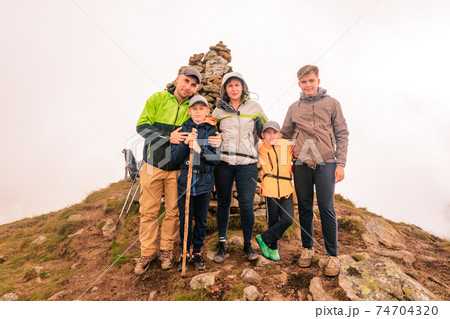 A family of tourists on top of a cloudy mountain in the Carpathians, the mountain of two thousand Gutin Tomnatyk, bold tourists in the mystical white clouds. 74704320