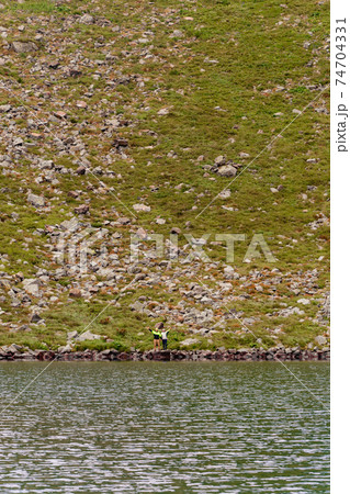 A couple of tourists stand on the edge of a mountain lake, Lake Brebeneskul, the Montenegrin ridge, the Carpathians of Ukraine. A couple of tourists stand on the edge of a mountain lake, Lake Brebeneskul, the Montenegrin ridge, the Carpathians of Ukraine. 74704331